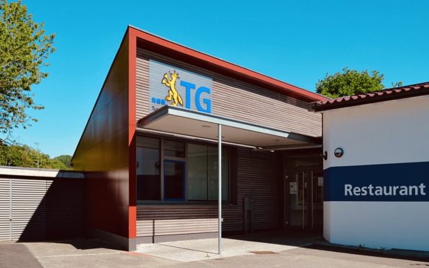 Eingang des TG Restaurants mit modernem Design und sichtbarem Logo.