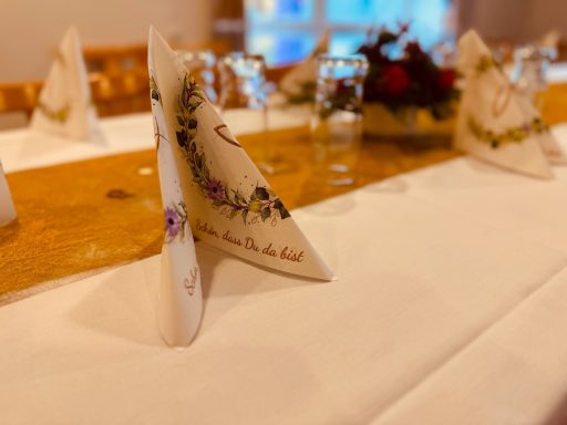 Stilvoll gedeckter Tisch mit dekorativ gefalteten Servietten und Blumenarrangement.