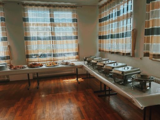 Buffet mit mehreren Warmhaltegeräten und einer Auswahl an Speisen in einem hellen Raum.